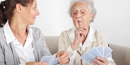 Eine Seniorin mit einer jüngeren Frau bei einem Kartenspiel