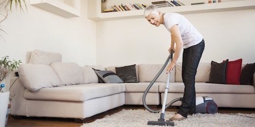 Eine Frau beim Staubsaugen in einem Wohnzimmer